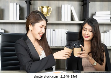 Office Coffee Break With Two Female Colleagues Sitting Chatting Over Cups Of Coffee. Asian Business Woman Holding Coffee Cup In Office.