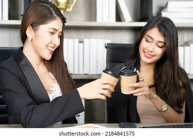 Office Coffee Break With Two Female Colleagues Sitting Chatting Over Cups Of Coffee. Asian Business Woman Holding Coffee Cup In Office.