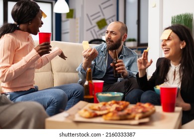 Office Colleagues Playing Guess Who Charades Game At Party Celebration With Alcoholic Drinks And Snacks. Cheerful People Using Sticky Notes To Have Fun And Do Leisure Activity After Work.