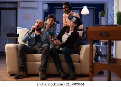 Office Colleagues Using Vr Headset And Joystick To Play Videogames At Party After Work. Man And Women Enjoying Virtual Reality Goggles And Online Game On Tv Console After Hours.