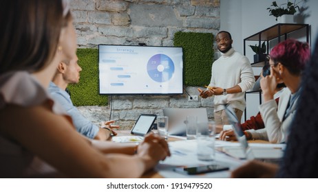 Office Conference Room Meeting: Black Chief Company Strategist Doing TV Presentation To A Diverse Team Of Multi-Ethnic Professional Businesspeople, Explaining Marketing Strategy, Data Analysis