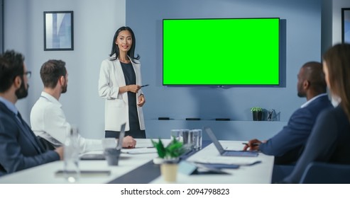 Office Conference Room Meeting Presentation: Motivated Businesswoman Talks, Uses Green Screen Chroma Key Wall TV. Successfully Presenting E-Commerce Product To Group Of Multi-Ethnic Investors