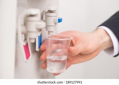 Office Cooler. Close-up Of Woman Filling Styrofoam Cup At Water Cooler