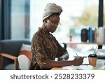 Office, desk and black woman writing with documents for project research, report and creative job. Journalist, turban and planning with laptop at company for magazine, article and publishing in Kenya