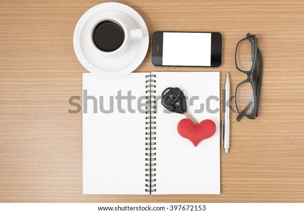 office desk : coffee and phone with car\
key,eyeglasses,notepad,heart on wood\
background