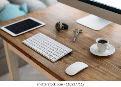 Office desk with computer, tablet and cup of coffee