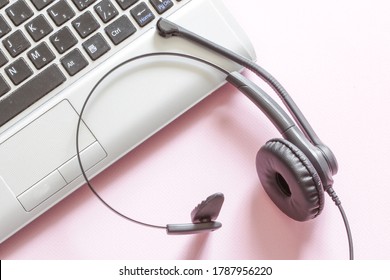 Office Desk With Headset And Keyboard On The Pink Background. Telecommuting. Remote Operation. Top View. Horizontal Orientation