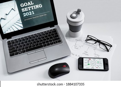 Office desk items with laptop for presentation of Goal setting 2021, tumblr, smartphone, mouse computer, paper note and eye glasses