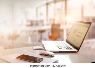 office desk with laptop smart phone and business office background.