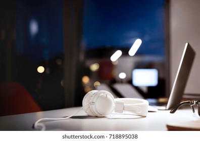 Office Desk At Night With Computer And Earphones.