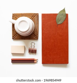 Office Desk. Notebook, Colored Pencel, Clip, Eraser, Cup On White Background. Top View, Copy Space