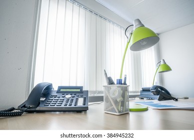 Office Desk With A Phone And Green Lamps