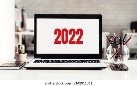 Office desk with red 2022 loading bar on laptop screen for happy new year concept