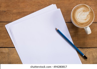 Office Desk Table With Blank Paper Page, Pencil And Cup Of Coffee.Top View With Copy Space.Office Supplies And Gadgets Concept.