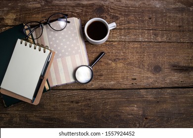 Office Desk Table With Coffee Cup, American History Book, Pen, Notebook And Eyeglasses. Educations, Resolutions, Goal, Plan, Strategy, Politics, International Relations Concept