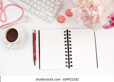 Office desk table with computer, cup of coffee and peony flowers. White wooden background.