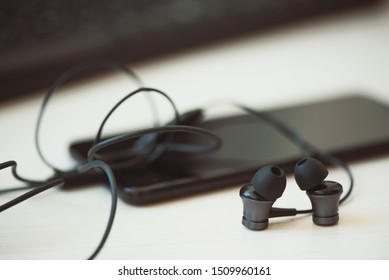Office desk table with computer, smartphone, and headphones. Essential items black color on light desk.  Workplace concept