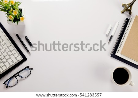 Office desk table with keyboard, notebook, pen, cup of coffee and flower. Top view with copy space (selective focus)

