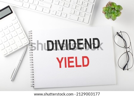 Office desk table with keyboard, notepad and calculator. Top view text DIVIDEND YIELD