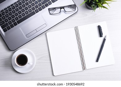 Office desk table with laptop, smart phone, cup of coffee and supplies, on wooden background. Top view with copy space, flat lay