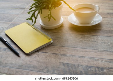 office desk table with a note book, pen, cactus and white cup coffee for working in top view