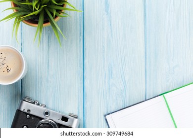 Office Desk Table With Notepad, Camera, Coffee And Flower. Top View With Copy Space