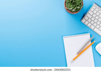 Office desk table with notepad, plant and supplies. Top view with copy space. Flat lay