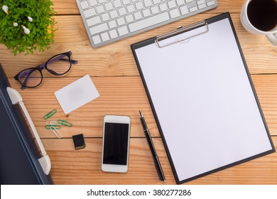 Office desk table with smartphone, pen on notebook, name card, cup of coffee and flower. Top view with copy space (selective focus) - Powered by Shutterstock