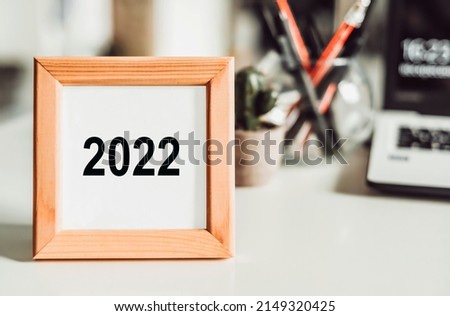 Office desk with office tools and a photo frame with 2022 numbers inside