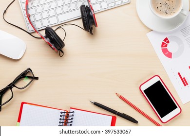 Office desk workplace with smart phone, charts and coffee on wooden table. Top view with copy space