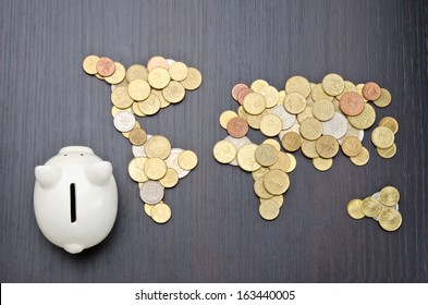 Office Desk With World Map Made Of Money Coins And Piggy Bank