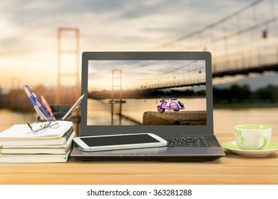 office desk,notebook computer,tablet,coffee cup,book,pen,pencil on wooden table over landscape of bamboo bridge with lighting of sunset background,selective focus at monitor - Powered by Shutterstock
