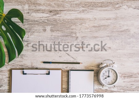 Office desktop background with computer keyboard, notepad, pencil, vintage alarm clock and plant. Home office concept.