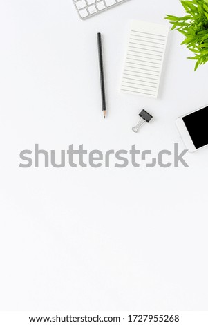 Office desktop concept. Notebook, computer keyboard, phone, pen and flower on white background. Top view