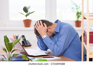 Office employee clutching his head in his hands while reading a document.