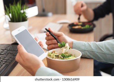 Office Employee With Smartphone Having Lunch At Workplace, Closeup. Food Delivery