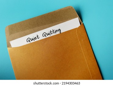 Office envelope and document with handwritten text QUIET QUITTING, when employees not engaged or taking job seriously, do minimum required but focus on job outside office