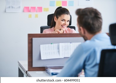 Office flirt - attractive woman flirting over desk with her coworker
