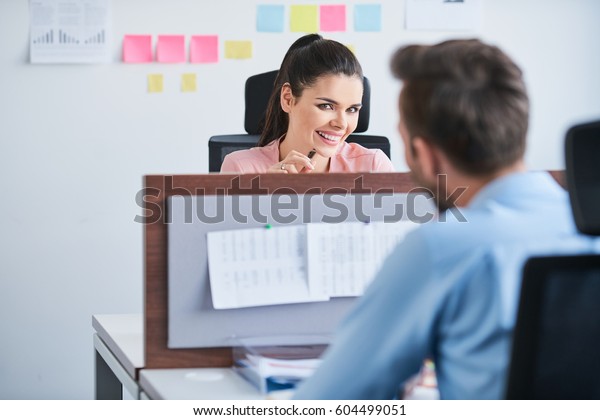 Office flirt - attractive woman flirting over\
desk with her coworker