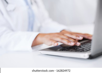 office, health, medicine, technology and internet concept - female doctor using her laptop computer - Powered by Shutterstock