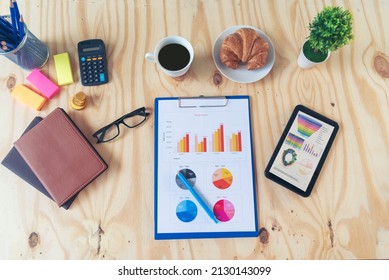 Office Laptop Business Financial Document Chart And Graph On Wooden Table With Coffee Cup. Flat Lay Notebook Computer Laptop On Office Desk. No People Business Graph Chart Mockup On Business Workspace