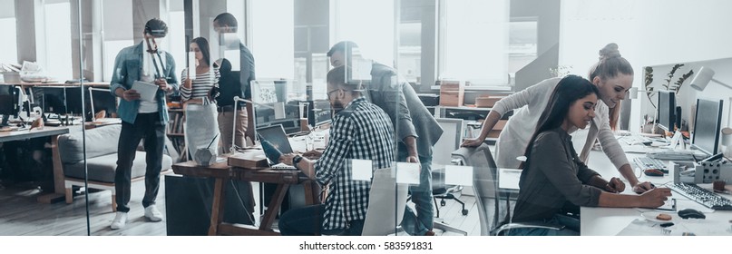 Office life. Group of young business people working and communicating together in creative office - Shutterstock ID 583591831