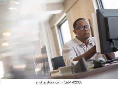 Office life. A man seated at a desk using a computer. - Shutterstock ID 1664702338