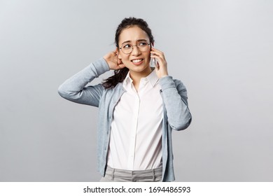 Office lifestyle, business and people concept. Reluctant unsure asian girl scratch back of head indecisive, have phone conversation, looking away troubled, feel awkward as rejecting offer for date