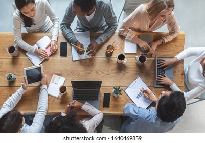 Office Lifestyle Concept. Top View Of International Young Business Team Having Meeting At Office, Sitting Around Table