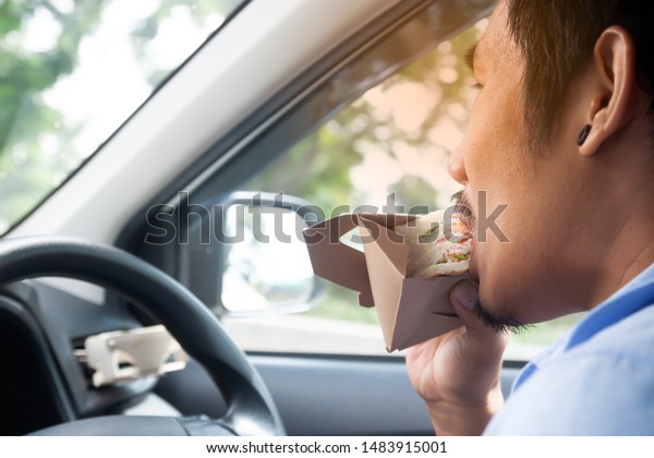 Office man eating sandwich while driving to\
work. Morning routine.\
Lifestyle