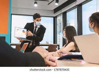 Office Man Wearing Mask Present Milestone And Work Progress With Team In Meeting Room. New Normal Office. Keep Physical Distancing.