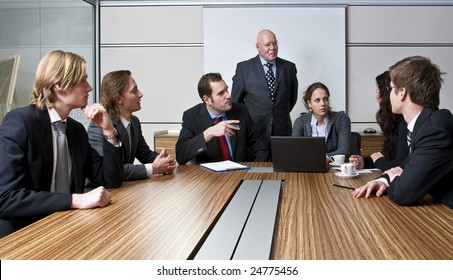 An Office Meeting Between A Senior Executive And Six Of His Junior Staff Members