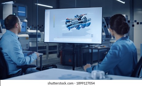 Office Meeting: Confident Female Engineer Talks To Project Manager, Watching Interactive Digital Whiteboard TV That Shows New Sustainable Eco-Friendly Engine 3D Concept. Modern Factory With Machinery