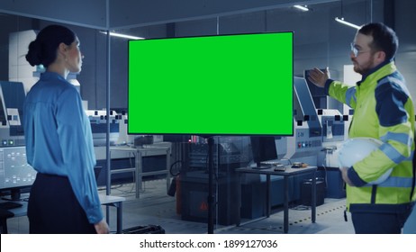 Office Meeting: Confident Female Project Manager To Chief Engineer, Watching Interactive Digital Whiteboard TV That Shows Green Screen Chroma Key Display. Modern Factory With Machinery